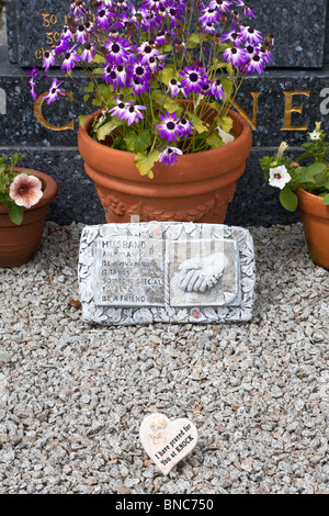 Fleurs et plaque avec message personnel en face de pierre tombale, Co Galway, Irlande Banque D'Images