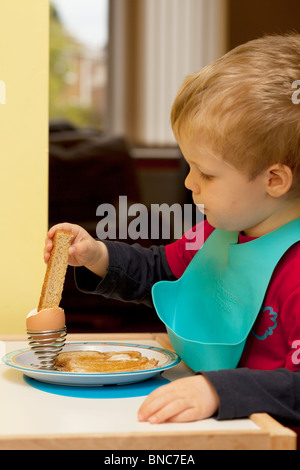 Jeune garçon de manger un oeuf à la coque pour le petit déjeuner Banque D'Images