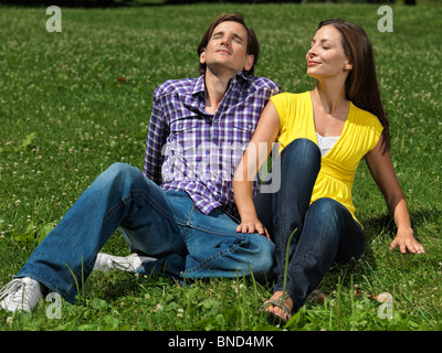 Jeune couple heureux au début de la trentaine assis sur l'herbe dans un parc Banque D'Images