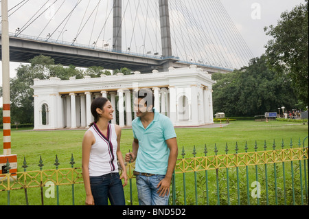 Couple avec un mémorial et un pont à l'arrière-plan, James Famille Prinsep Memorial, Vidyasagar Setu, Kolkata, West Bengal, India Banque D'Images