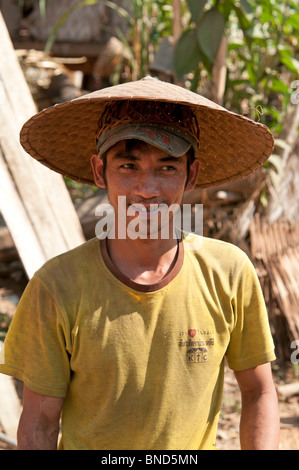 Ajo un homme portant un chapeau conique dans un village tribal du nord du Laos Banque D'Images