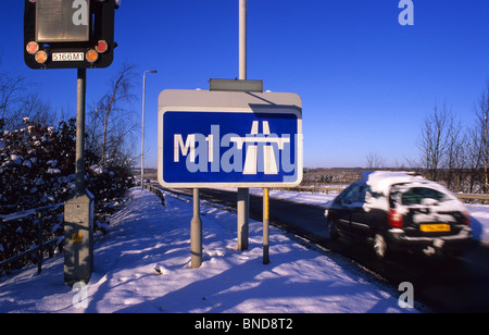 Une voiture passe roadsign affirmant début de l'autoroute M1 dans la neige de l'hiver près de Leeds Yorkshire UK Banque D'Images