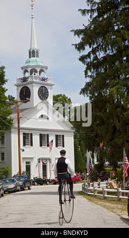 Un homme d'une des tours de roue haute antique location près d'une église de la congrégation à la suite d'une parade le 4 juillet Banque D'Images