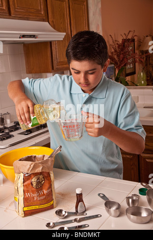 MinorityTeenage ethniques Hispanic boy wearing a blue shirt mesurer les ingrédients de cuisson. M. © Myrleen Pearson Banque D'Images