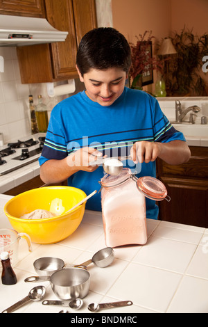 Teenage boy wearing a blue shirt mesurer les ingrédients de cuisson. M. © Myrleen Pearson Banque D'Images