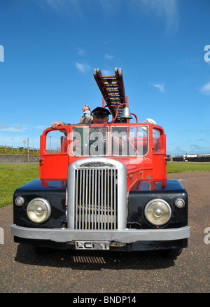 Une miniature 1950 fire engine. Un pilote se prépare à prendre un peu d'enfants pour une balade en elle. Banque D'Images