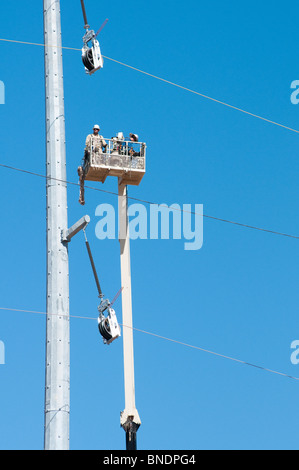 Deux travailleurs de la construction d'une grue panier travailler sur une nouvelle ligne de transmission. Banque D'Images