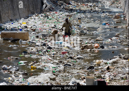 L'homme à une poubelle rempli Rivière, Port au Prince, Haïti, Caraïbes Banque D'Images