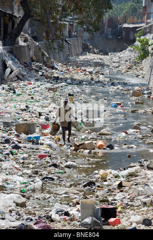 L'homme à une poubelle rempli Rivière, Port au Prince, Haïti, Caraïbes Banque D'Images