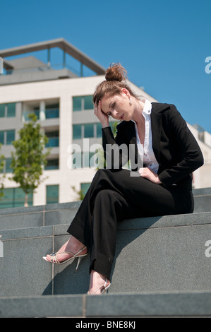 Jeune femme d'affaires inquiets de l'emplacement en plein air dans l'herbe - Chef dans la main Banque D'Images