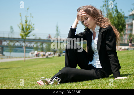 Jeune femme d'affaires inquiets de l'emplacement en plein air dans l'herbe - Chef dans la main Banque D'Images