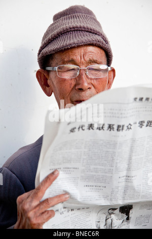 Old Man reading newspaper in Shangri-La Zhongdian ou dans la province du Yunnan, Chine Banque D'Images