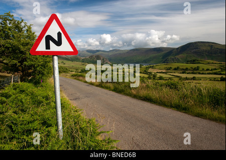 Signe de route sur des routes rurales d'avertissement étroite route sinueuse de l'avant. Banque D'Images