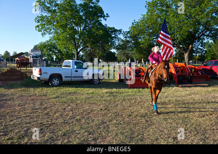 Cowgirl waving flag en bestiaux avant la cérémonie d'ouverture de l'érythroblastopénie événement rodéo au Texas, USA