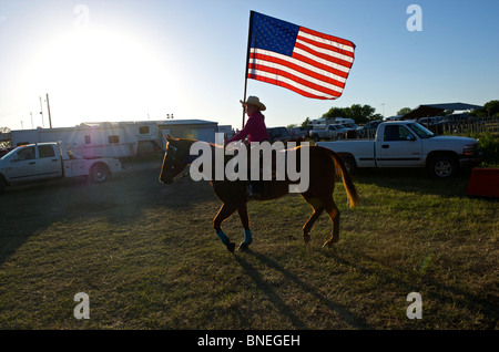 Cowgirl en agitant le drapeau américain à la cérémonie d'ouverture de l'érythroblastopénie événement rodéo au Texas, USA