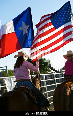 Cowgirls waving flag en bestiaux sur la cérémonie d'ouverture de l'érythroblastopénie événement rodéo au Texas, USA Banque D'Images