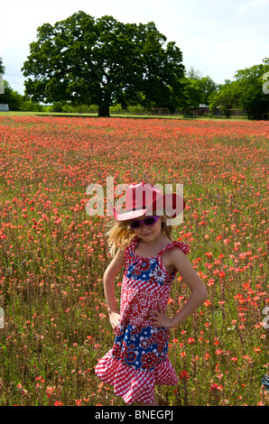 Fille dans domaine de rouge lumineux de fleurs de printemps dans le Texas, USA Banque D'Images