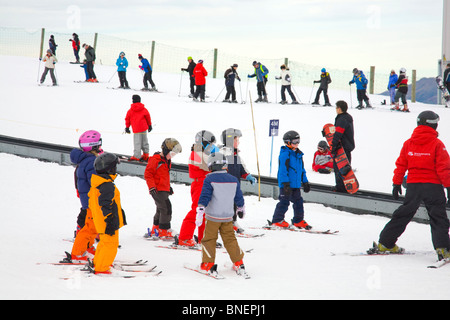 Les enfants avec leur moniteur de ski apprennent à skier à Coronet Peak station de ski tandis que d'autres apprenants voyagent sur le tapis magique, Queenstown, Nouvelle-Zélande Banque D'Images