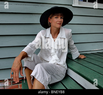 Femme modèle femme en chapeau noir cerclée de large avec chemisier blanc à la caméra directement dans les mains de la mode Banque D'Images