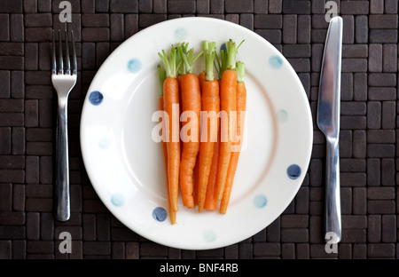 Assiette santé de bébé fraîchement préparés carottes mûres nettoyé et prêt pour la cuisson sur une table mise à plat et non pas avec les gens Banque D'Images