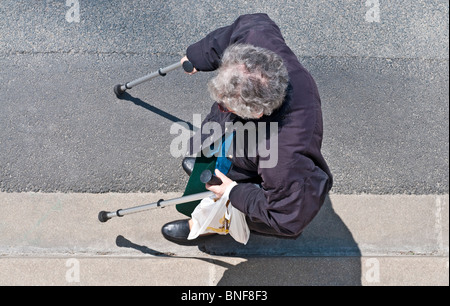 Femme âgée avec des bâtons d'étrier marchant à côté trottoir - France. Banque D'Images