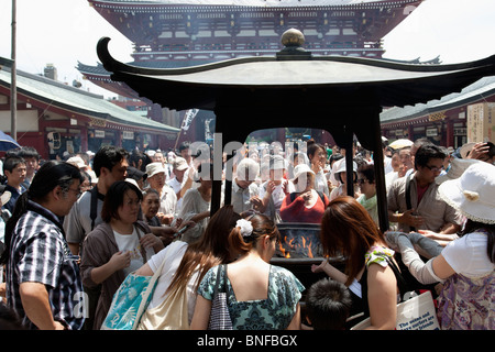 Rassemblement de personnes autour d'un brûleur de la fumée d'encens. Le temple Senso-ji d'Asakusa à Tokyo. Banque D'Images