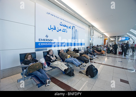 Les voyageurs se reposer sur des chaises longues à l'Aéroport International de Dubaï, DUBAÏ, ÉMIRATS ARABES UNIS. Banque D'Images