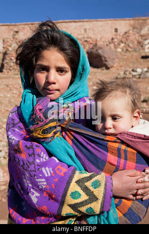 Jeune femme vivant dans une ferme traditionnelle avec un bébé, près de Telouet, montagnes du Haut Atlas, Maroc Banque D'Images