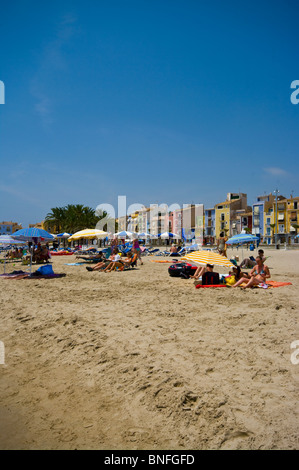 Les gens à vous détendre sous les parasols sur la plage de Villajoyosa, avec des bâtiments de style mauresque dans l'arrière-plan Banque D'Images