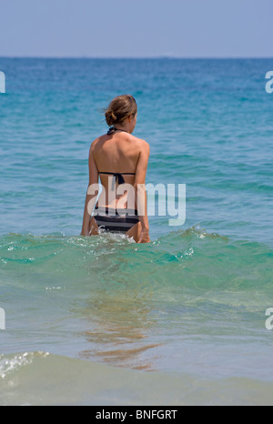 Jeune femme mince dans un bikini de marcher dans la mer Banque D'Images