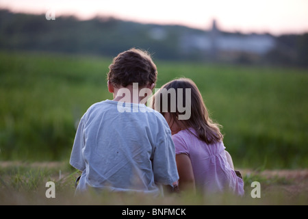 Frère et soeur de mêmes parents bénéficiant d'une soirée tranquille à l'extérieur dans une ferme Banque D'Images