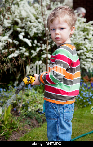 Jeune garçon d'arroser les fleurs dans le jardin. Banque D'Images