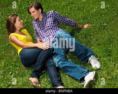 Jeune couple heureux au début de la trentaine lying on grass in a park Banque D'Images