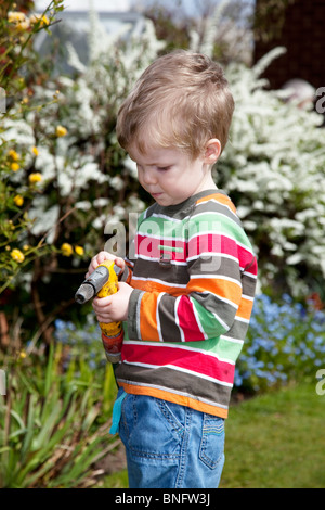 Jeune garçon d'arroser les fleurs dans le jardin. Banque D'Images