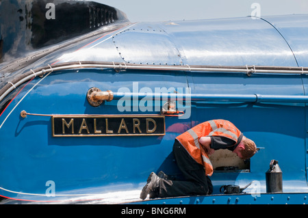 Workman l'entretien des contrôles sur le train à vapeur Mallard. Banque D'Images