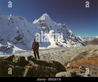 Un porteur népalais se dresse sur un éperon rocheux avec pointe en coin et le Kangchenjunga Glacier derrière, est du Népal Banque D'Images