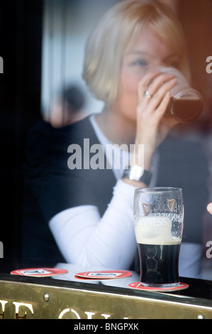 Fille boit un Guinness dans Dublin pub Banque D'Images