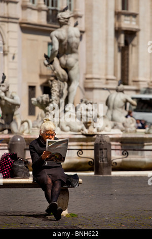 Femme plus âgée se détendre avec un journal le dimanche matin sur la Piazza Navona, Rome Lazio Italie Banque D'Images