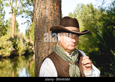 Plus beau cowboy à mâcher sur un peu de foin, appuyé contre un arbre Banque D'Images