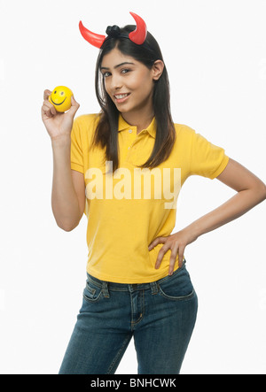 Portrait d'une femme portant des cornes du diable et tenant une balle smiley Banque D'Images