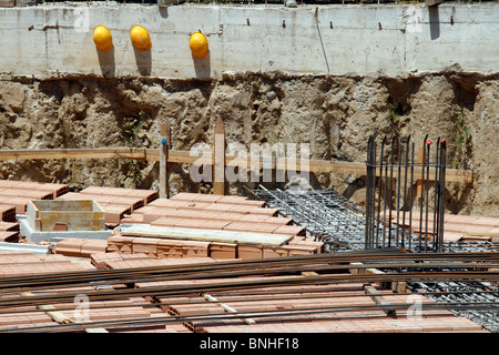 Trois constructeurs casque protecteur des casques sur mur sur chantier Banque D'Images