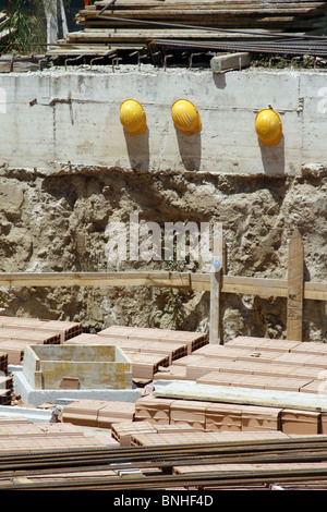 Trois constructeurs casque protecteur des casques sur mur sur chantier Banque D'Images