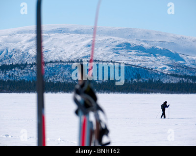 Un skieur fait son chemin au-dessus du lac gelé Kaalasjärvi à Kiruna, en Laponie, le nord de la Suède. Banque D'Images