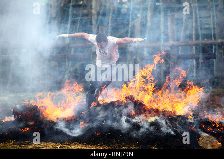 Saut d'un concurrent par le feu à l'infâme course tough guy à Wolverhampton, en Angleterre. Banque D'Images