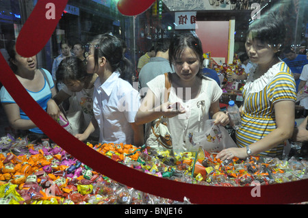 Les femmes achètent des bonbons dans une rue de marché de nuit à Wangfujing, Beijing, Chine Banque D'Images