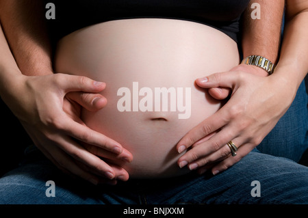 Une femme enceinte ventre se serra par la mère et le père, seul le ventre et les mains et les bras. Banque D'Images