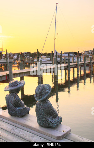 Statues de l'enfant sur un quai au coucher du soleil, Silver Lake Harbour, Ocracoke Island, Cape Hatteras National Seashore, North Carolina, USA Banque D'Images