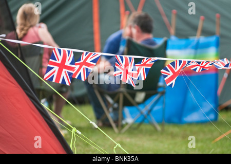 Dimanche matin, et les gens sont assis autour de leurs tentes derrière Patriotic Union Jack noir au festival de musique WOMAD 2010. Banque D'Images