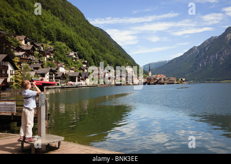 Hallstatt, Salzkammergut, Autriche. Garçon à la recherche au moyen d'un télescope à world cultural heritage village sur le lac Hallstattersee Banque D'Images