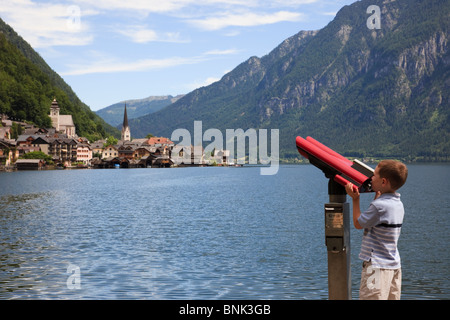 Garçon à la recherche au moyen d'un télescope à world cultural heritage village sur Hallstattersee lake. Hallstatt, Salzkammergut, Autriche. Banque D'Images